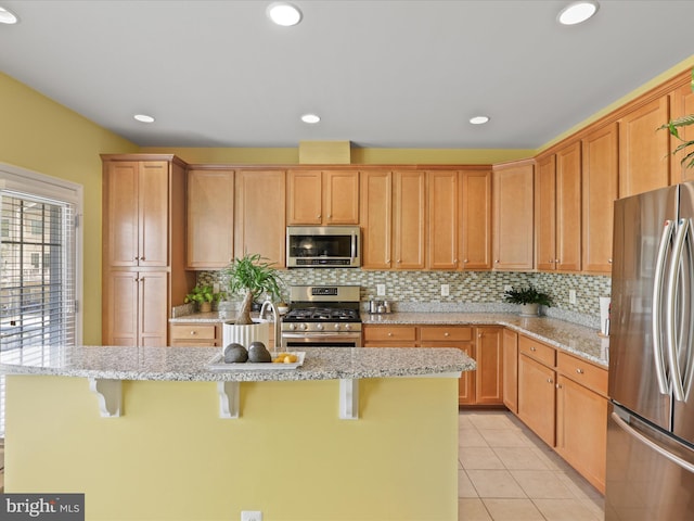 43559 Wheadon Ter, Chantilly, VA 20152 - kitchen featuring stainless steel appliances, a kitchen bar, decorative backsplash, light stone counters, and recessed lighting
