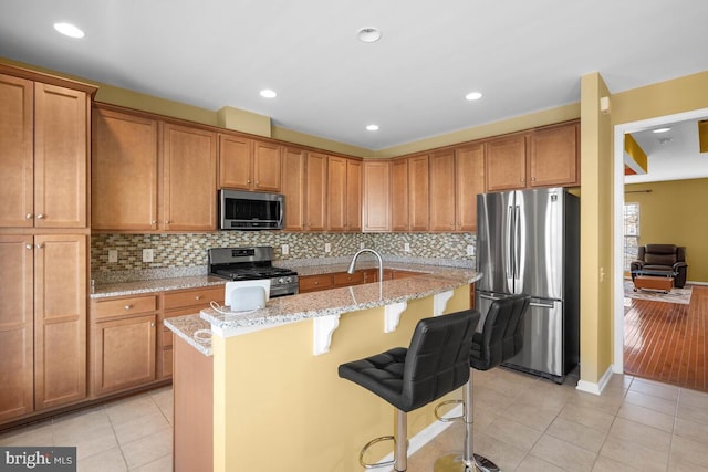 43559 Wheadon Ter, Chantilly, VA 20152 - kitchen with appliances with stainless steel finishes, light tile patterned floors, a breakfast bar, a center island with sink, and recessed lighting