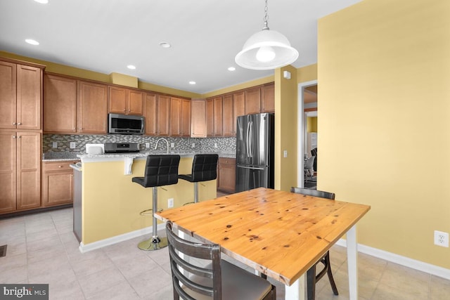 43559 Wheadon Ter, Chantilly, VA 20152 - kitchen with appliances with stainless steel finishes, a kitchen bar, tasteful backsplash, light countertops, and brown cabinets