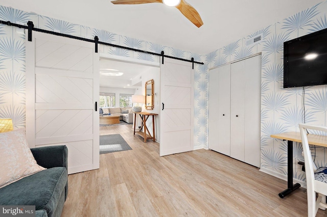 8002B Brighton Trl, Bethany Beach, DE 19930 - unfurnished office featuring a barn door, wood finished floors, wallpapered walls, and a ceiling fan