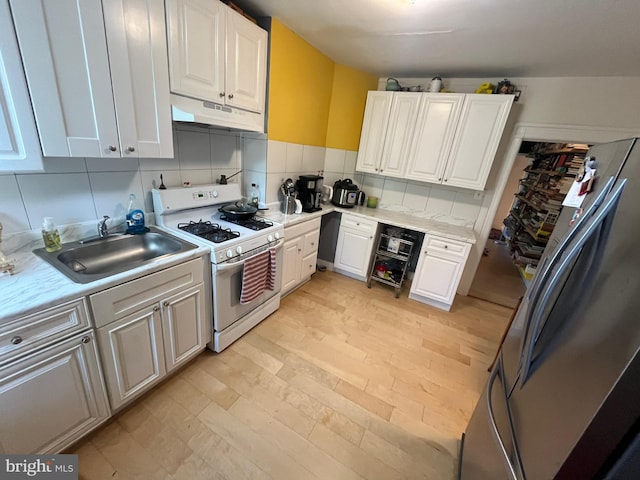 713 E 23rd St, Baltimore, MD 21218 - kitchen featuring white gas stove, freestanding refrigerator, under cabinet range hood, light countertops, and white cabinetry
