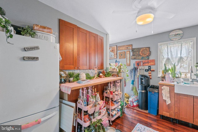 4433 Forest View Ave, Baltimore, MD 21206 - kitchen with freestanding refrigerator, brown cabinetry, dark wood-style floors, and decorative backsplash