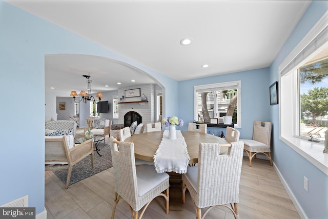 44 Harbor Ln, Long Beach Township, NJ 08008 - dining room with light wood-type flooring, arched walkways, recessed lighting, a chandelier, and a brick fireplace