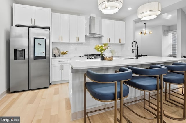 3708 Fairview Ave, Baltimore, MD 21216 - kitchen featuring stainless steel fridge with ice dispenser, wall chimney exhaust hood, white cabinets, light countertops, and a kitchen bar