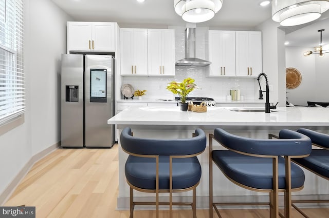 3708 Fairview Ave, Baltimore, MD 21216 - kitchen featuring stainless steel fridge, wall chimney exhaust hood, decorative backsplash, light wood-style floors, and a breakfast bar