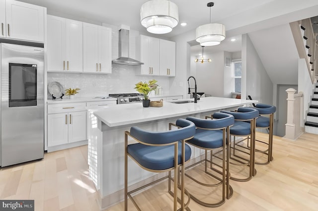 3708 Fairview Ave, Baltimore, MD 21216 - kitchen with fridge, wall chimney range hood, light wood finished floors, white cabinetry, and recessed lighting