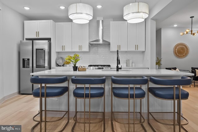 3708 Fairview Ave, Baltimore, MD 21216 - kitchen featuring wall chimney exhaust hood, stainless steel refrigerator with ice dispenser, decorative backsplash, light wood-type flooring, and recessed lighting