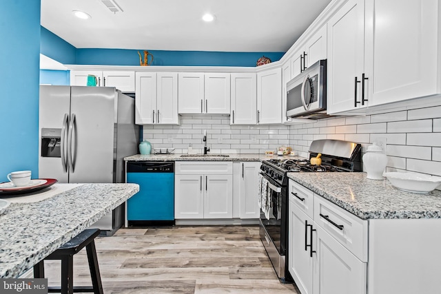 5309 Ethelbert Ave, Baltimore, MD 21215 - kitchen featuring stainless steel appliances, white cabinets, light wood finished floors, backsplash, and recessed lighting