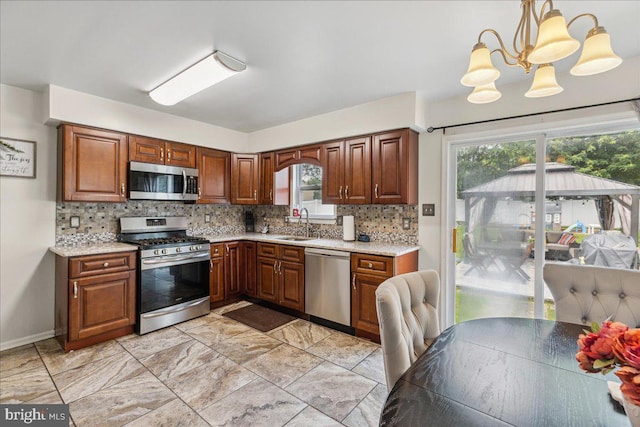 45 Sassafras Dr, Sicklerville, NJ 08081 - kitchen featuring stainless steel appliances, backsplash, a chandelier, and brown cabinets