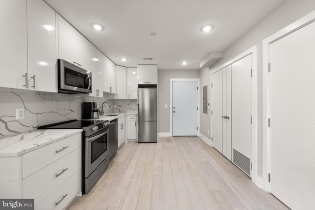 1638 K St NE Unit 101, Washington, DC 20002 - kitchen featuring stainless steel appliances, white cabinetry, light wood-style floors, backsplash, and recessed lighting