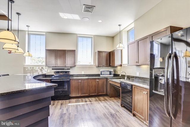 4163 S Four Mile Run Dr Unit 401, Arlington, VA 22204 - kitchen featuring black appliances, light wood-style floors, pendant lighting, decorative backsplash, and dark stone counters