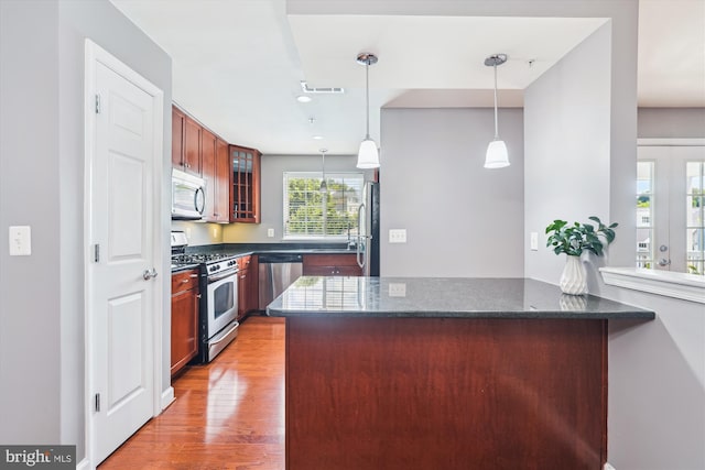 4163 S Four Mile Run Dr Unit 401, Arlington, VA 22204 - kitchen with appliances with stainless steel finishes, glass insert cabinets, light wood finished floors, hanging light fixtures, and dark stone counters