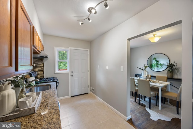 4703 Williston St, Baltimore, MD 21229 - kitchen featuring brown cabinetry, dark stone countertops, and under cabinet range hood