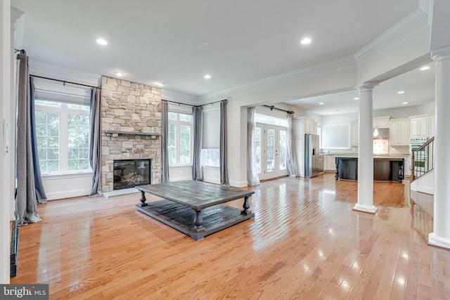 10002 Courthouse Rd, Vienna, VA 22181 - unfurnished living room featuring a stone fireplace, decorative columns, crown molding, light wood finished floors, and stairs