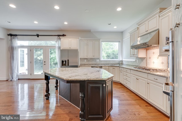 10002 Courthouse Rd, Vienna, VA 22181 - kitchen with under cabinet range hood, stainless steel appliances, decorative backsplash, a kitchen island, and recessed lighting