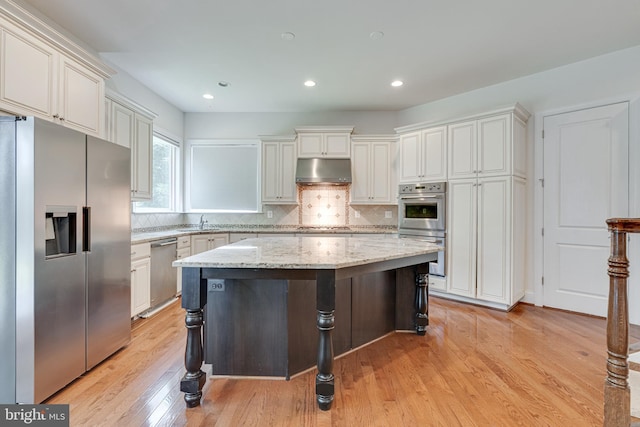 10002 Courthouse Rd, Vienna, VA 22181 - kitchen featuring stainless steel appliances, under cabinet range hood, a center island, light wood finished floors, and backsplash