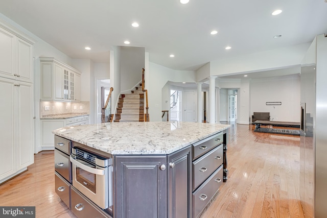 10002 Courthouse Rd, Vienna, VA 22181 - kitchen featuring white cabinetry, decorative columns, open floor plan, light wood-style flooring, and a kitchen island