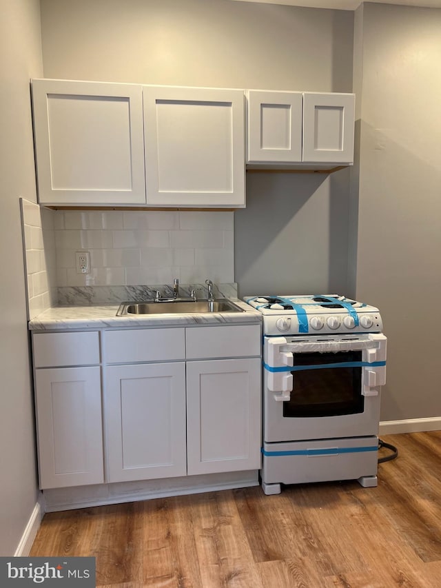 2036 W Ontario St, Philadelphia, PA 19140 - kitchen featuring white range with gas cooktop, white cabinets, backsplash, and light wood-style flooring