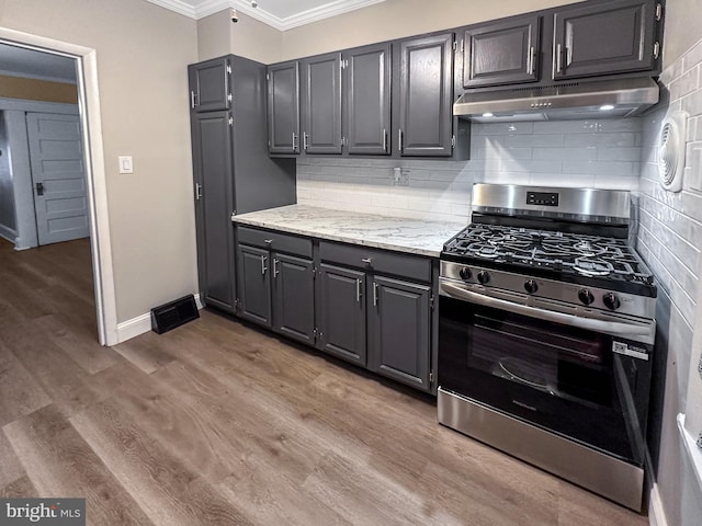 171 N York St, Pottstown, PA 19464 - kitchen with stainless steel gas stove, under cabinet range hood, ornamental molding, tasteful backsplash, and light wood finished floors