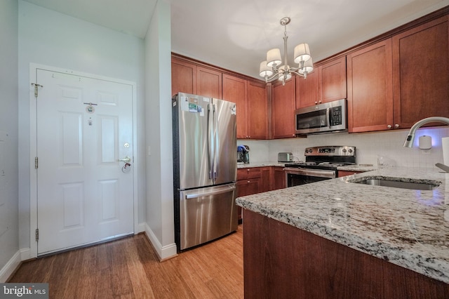 1000 Fountanview Cir, Newark, DE 19713 - kitchen with appliances with stainless steel finishes, light wood-style flooring, light stone counters, a chandelier, and brown cabinets