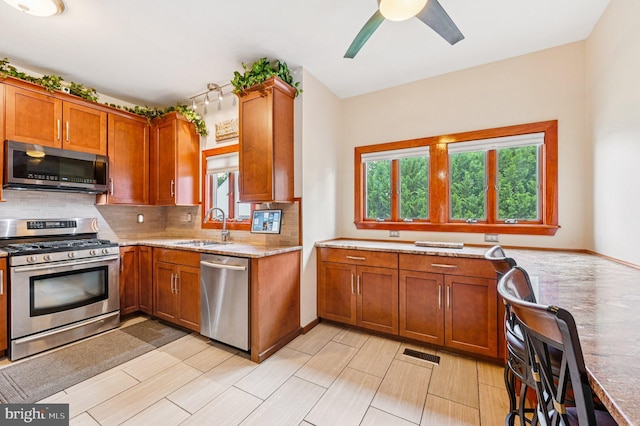 1802 Disney Estates Cir, Severn, MD 21144 - kitchen with appliances with stainless steel finishes, tasteful backsplash, brown cabinets, and ceiling fan