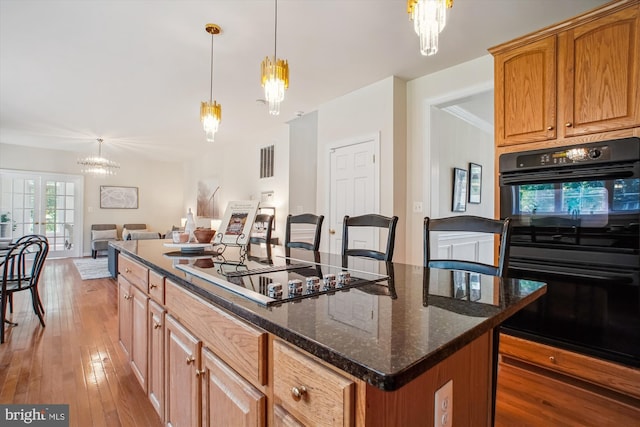 2907 Dumas St, Alexandria, VA 22306 - kitchen with black appliances, light wood finished floors, open floor plan, a kitchen island, and a chandelier