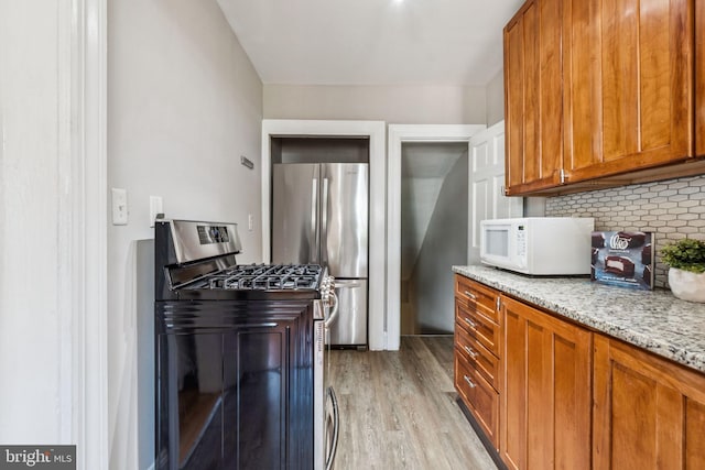 1818 Newton St NE, Washington, DC 20018 - kitchen with stainless steel appliances, backsplash, brown cabinetry, light wood-style floors, and light stone countertops