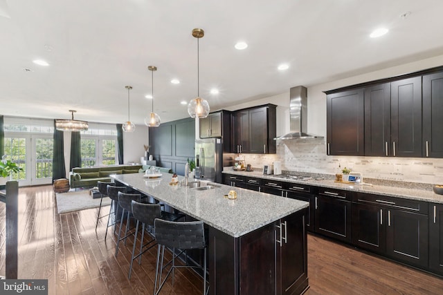 5445 Stream Bank Ln, Greenbelt, MD 20770 - kitchen with wall chimney range hood, appliances with stainless steel finishes, dark wood-type flooring, a kitchen breakfast bar, and light stone countertops