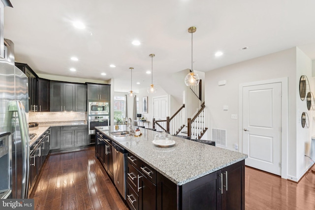 5445 Stream Bank Ln, Greenbelt, MD 20770 - kitchen featuring stainless steel appliances, dark wood-style flooring, light stone counters, a large island with sink, and recessed lighting