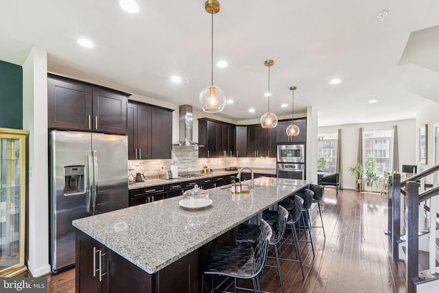 5445 Stream Bank Ln, Greenbelt, MD 20770 - kitchen with stainless steel appliances, wall chimney exhaust hood, backsplash, a large island with sink, and dark wood-type flooring