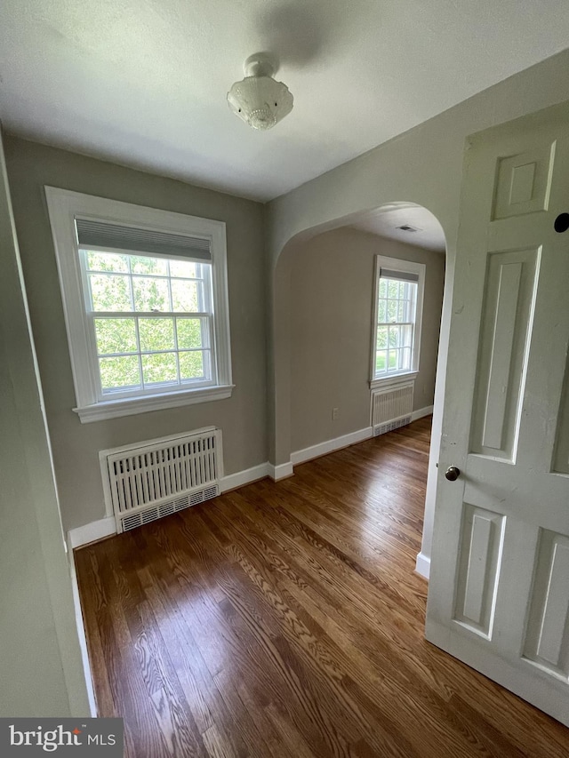 257 Jefferson St, Winchester, VA 22601 - unfurnished room featuring radiator, arched walkways, and wood finished floors