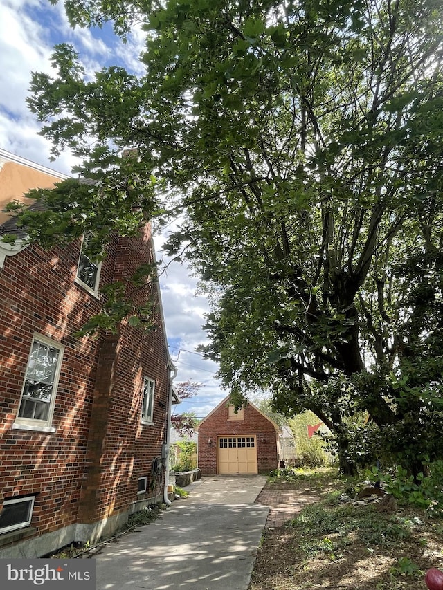 257 Jefferson St, Winchester, VA 22601 - view of side of home featuring an outdoor structure, brick siding, and concrete driveway