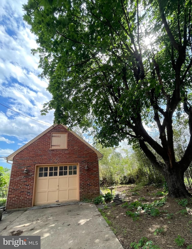 257 Jefferson St, Winchester, VA 22601 - view of home's exterior featuring brick siding, a garage, concrete driveway, and an outdoor structure