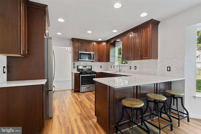 27 Brown Cir, Fredericksburg, VA 22405 - kitchen with appliances with stainless steel finishes, a peninsula, light wood-type flooring, tasteful backsplash, and recessed lighting