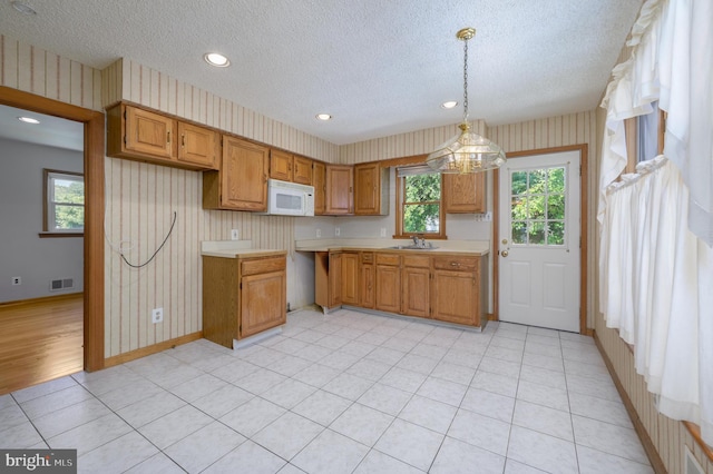 26 Rose Ln, Cherry Hill, NJ 08002 - kitchen with white microwave, wallpapered walls, a textured ceiling, light countertops, and brown cabinetry
