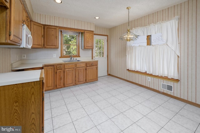 26 Rose Ln, Cherry Hill, NJ 08002 - kitchen featuring wallpapered walls, white microwave, light countertops, a textured ceiling, and brown cabinetry