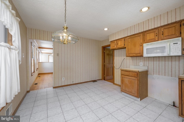 26 Rose Ln, Cherry Hill, NJ 08002 - kitchen featuring white microwave, wallpapered walls, brown cabinets, pendant lighting, and light countertops