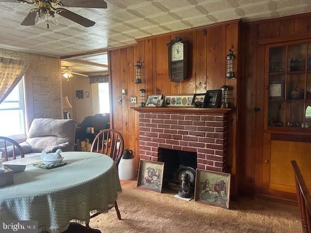 2012 E Main St, Douglassville, PA 19518 - carpeted dining area featuring ceiling fan, an ornate ceiling, a fireplace, and wood walls