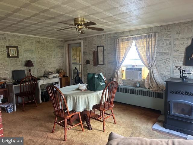 2012 E Main St, Douglassville, PA 19518 - carpeted dining area featuring a wood stove, radiator heating unit, cooling unit, a ceiling fan, and wallpapered walls