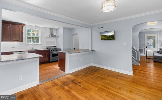 4 Haslet Way, Wilmington, DE 19807 - kitchen featuring high end range, wall chimney exhaust hood, arched walkways, a peninsula, and light wood-style flooring