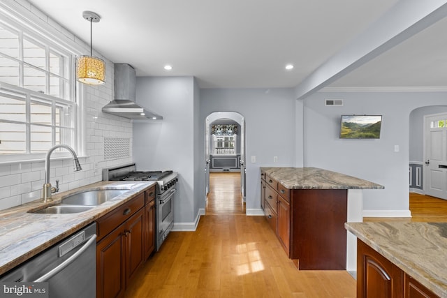 4 Haslet Way, Wilmington, DE 19807 - kitchen featuring stainless steel appliances, wall chimney range hood, arched walkways, decorative backsplash, and light wood-style floors