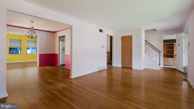 237 Louise Dr, Morrisville, PA 19067 - unfurnished living room with wood finished floors, a chandelier, stairs, and wallpapered walls
