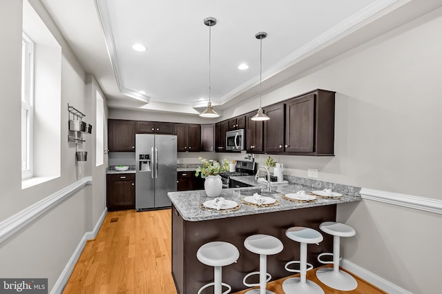 1717 Bank St, Baltimore, MD 21231 - kitchen with appliances with stainless steel finishes, dark brown cabinetry, a peninsula, light stone counters, and a breakfast bar area