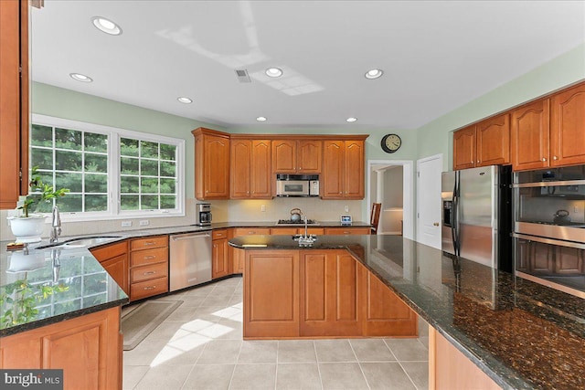 4 William Howard Dr, Glen Mills, PA 19342 - kitchen featuring appliances with stainless steel finishes, dark stone counters, light tile patterned flooring, recessed lighting, and brown cabinets