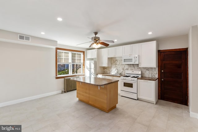 313 W 5th Ave, Conshohocken, PA 19428 - kitchen with white appliances, radiator, a center island, white cabinets, and tasteful backsplash