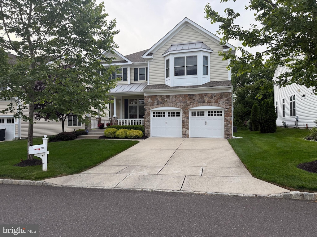 125 Starboard Way, Mount Laurel, NJ 08054 - view of front facade featuring stone siding, an attached garage, a front yard, concrete driveway, and a porch