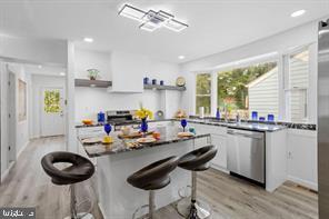 167 Kendall Blvd, Oaklyn, NJ 08107 - kitchen featuring stainless steel dishwasher, open shelves, light wood-type flooring, white cabinets, and a breakfast bar