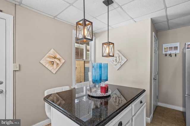 1511 Palm St, Reading, PA 19604 - kitchen featuring a paneled ceiling, dark stone counters, decorative light fixtures, freestanding refrigerator, and white cabinets
