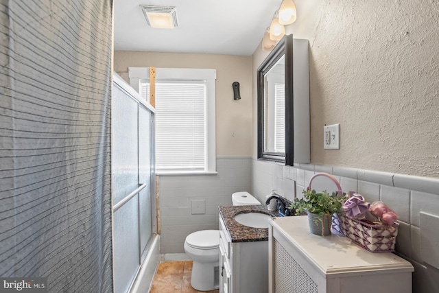 1511 Palm St, Reading, PA 19604 - bathroom with vanity, wainscoting, combined bath / shower with glass door, tile patterned flooring, and tile walls