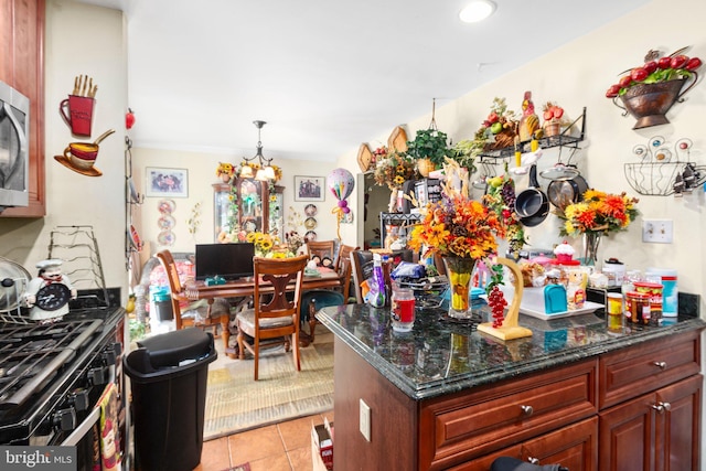 5955 Plumwood Ln, Woodbridge, VA 22193 - kitchen with light tile patterned flooring, range with gas stovetop, dark stone countertops, a chandelier, and stainless steel microwave